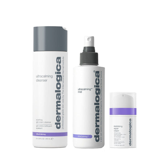 Die Routine Frühlingshaut Set enthält drei Dermalogica Produkte für empfindliche Haut: UltraCalming Cleanser, Ultracalming Mist und Barrier Repair Cream in einer schlichten weißen Verpackung mit grauen und violetten Akzenten, aufrecht stehend.