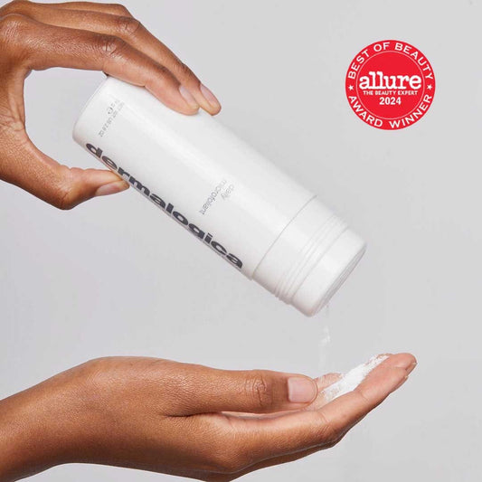 Eine Person schüttet sich Dermalogicas Daily Microfoliant, ein weißes Hautpflegeprodukt in Puderform, angereichert mit einem Skin Brightening Complex, in die Hand. Ein Abzeichen „Allure Best of Beauty 2024 Award Winner“ ist sichtbar.