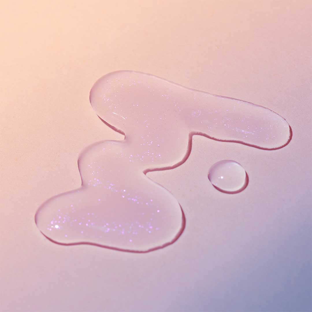 Klare Flüssigkeitströpfchen auf einer hellen Oberfläche mit einem Hintergrund mit sanftem Farbverlauf veranschaulichen die erfrischende Wirkung des Breakout Clearing Liquid Peel.