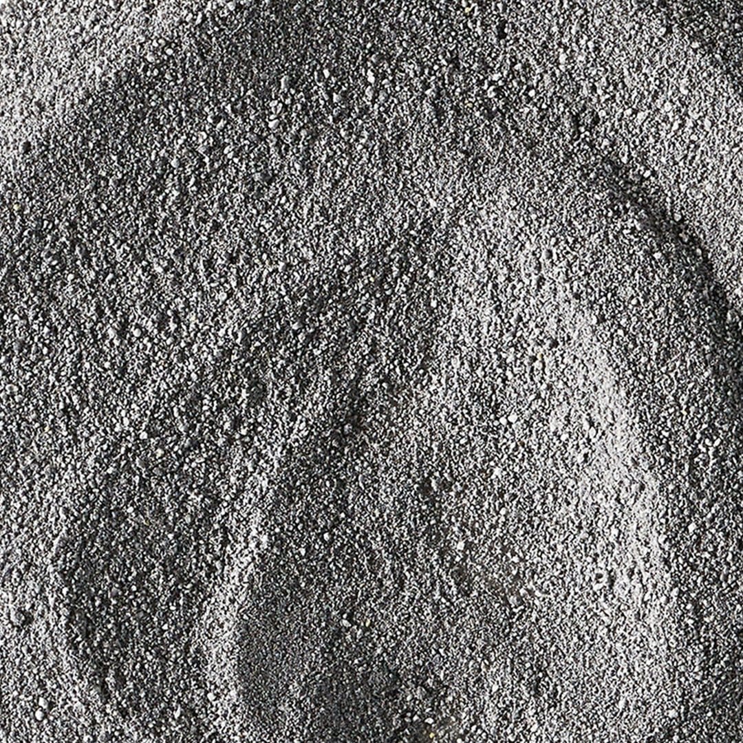 Nahaufnahme einer strukturierten grauen Daily Superfoliant-Puderoberfläche mit sichtbaren Wirbeln und ungleichmäßiger Verteilung, was auf seine potenzielle Rolle bei der Unterstützung der Kollagenproduktion hindeutet.