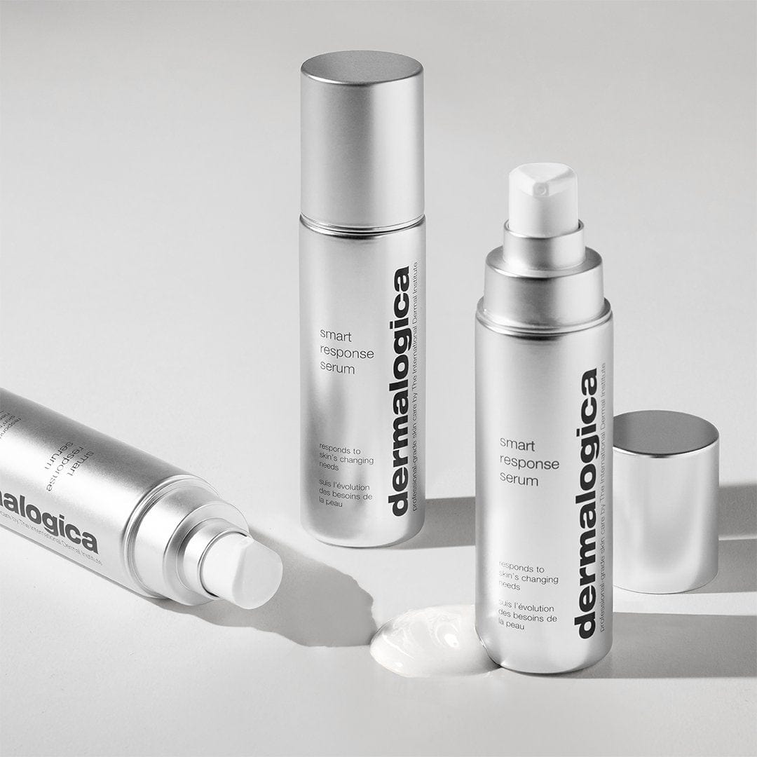 Drei silberne Flaschen Smart Response Serum werden auf einer weißen Fläche präsentiert; zwei stehen aufrecht, während eine liegt, neben der das Serum ausgegeben wurde.