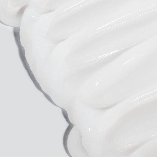 Nahaufnahme des weißen, cremigen Ultra Calming Cleanser mit einer glatten, welligen Textur vor einem hellgrauen Hintergrund - ideal für empfindliche Haut und inspiriert von Dermalogicas sanften Formeln.