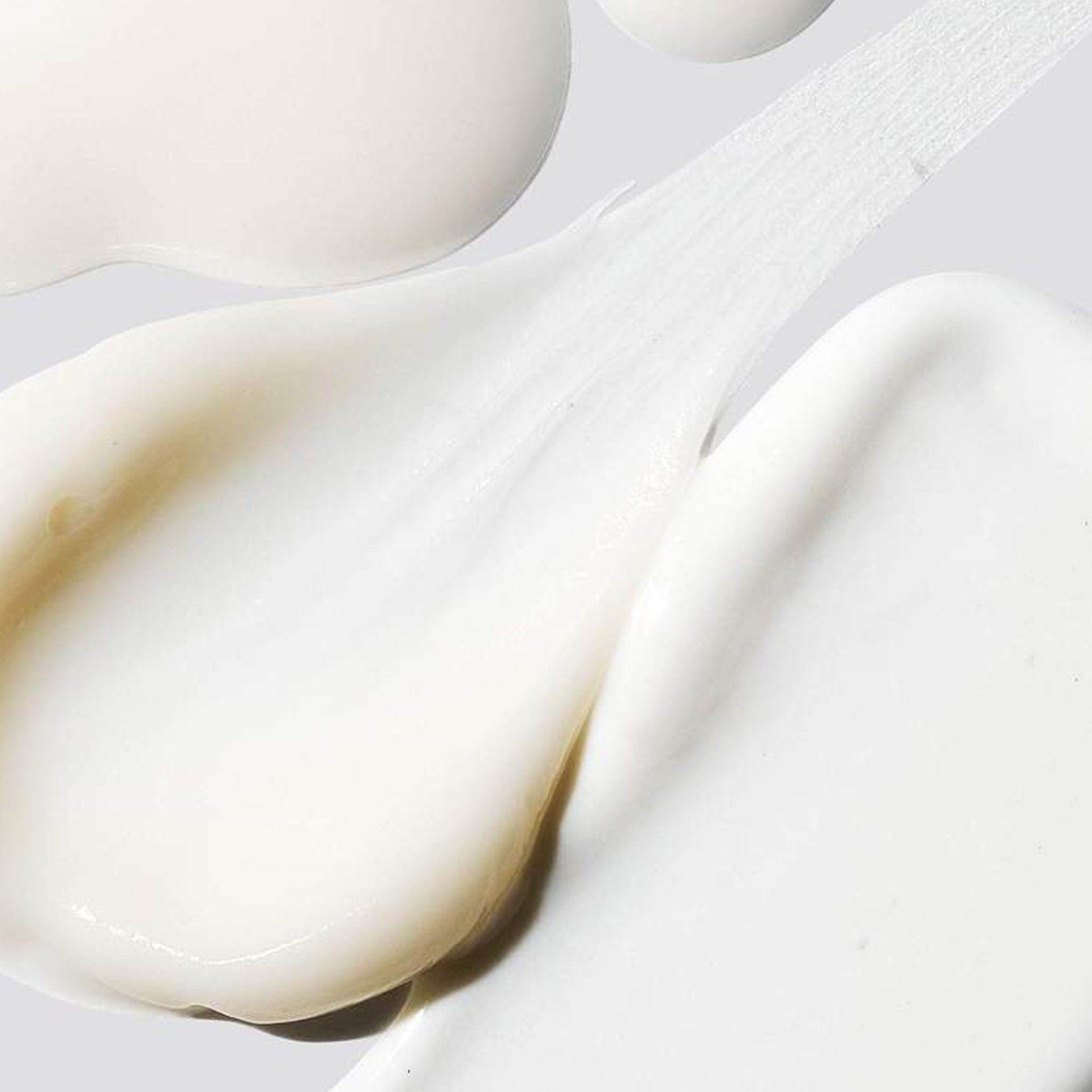 Nahaufnahme von verschmierten weißen Cremetupfern auf glatter Oberfläche.