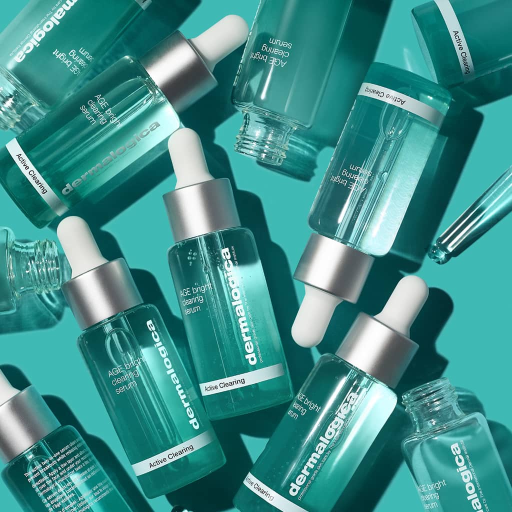 Mehrere Dermalogica-Serumfläschchen in Türkis mit Tropfern auf türkisem Hintergrund.