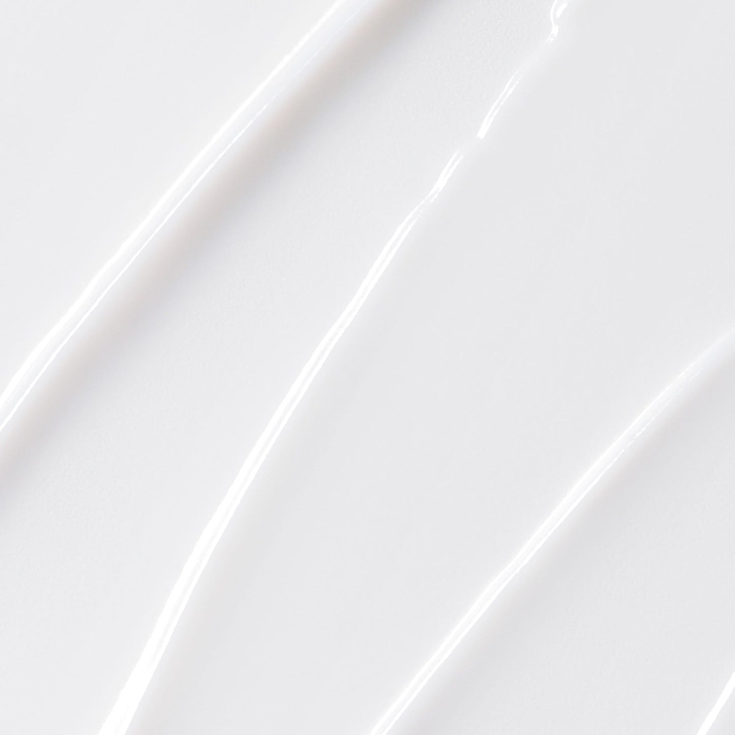 Nahaufnahme der glatten, weißen MultiVitamin Power Firm Anti-Aging-Creme, die in gleichmäßigen, strukturierten Linien auf einer ebenen Fläche verteilt ist.