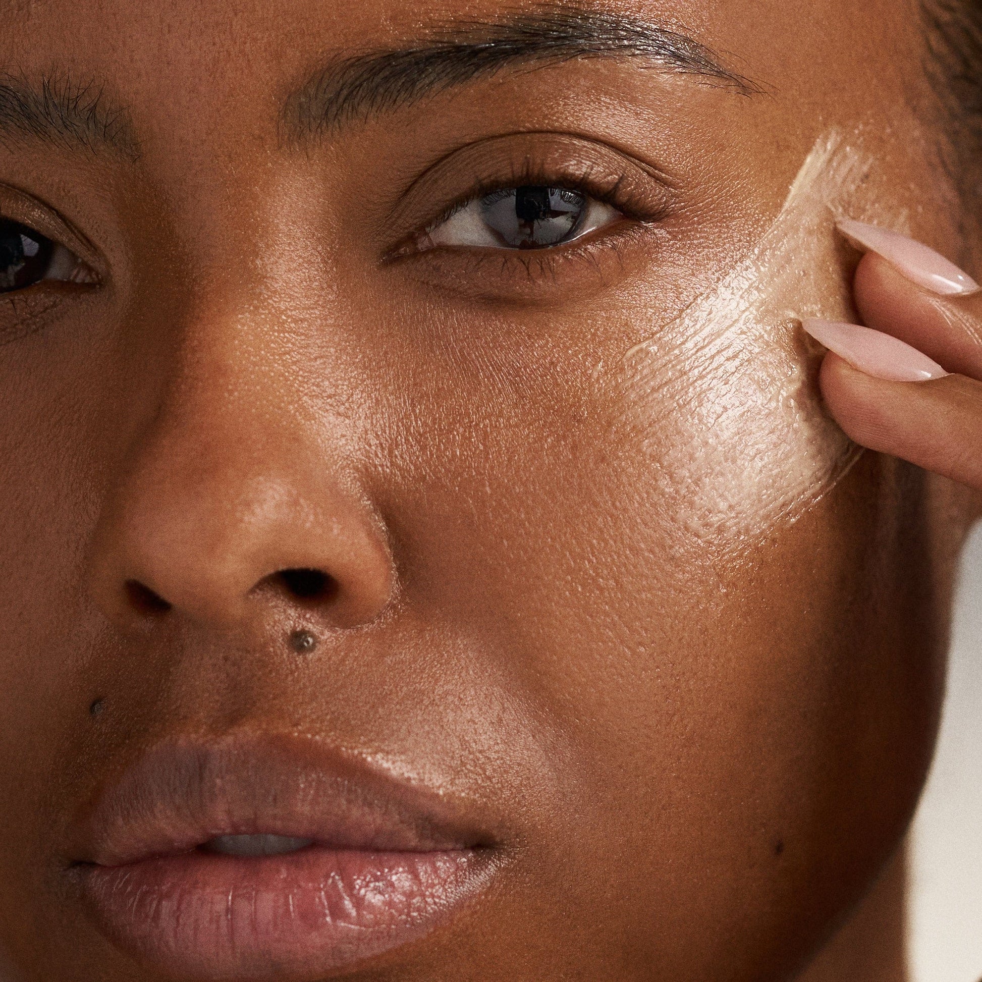 Die MultiVitamin Power Recovery Masque wird mit den Fingern auf die Wange aufgetragen, wobei der Schwerpunkt auf die Augenpartie gelegt wird, um die antioxidative Wirkung und die Verjüngung zu unterstützen.