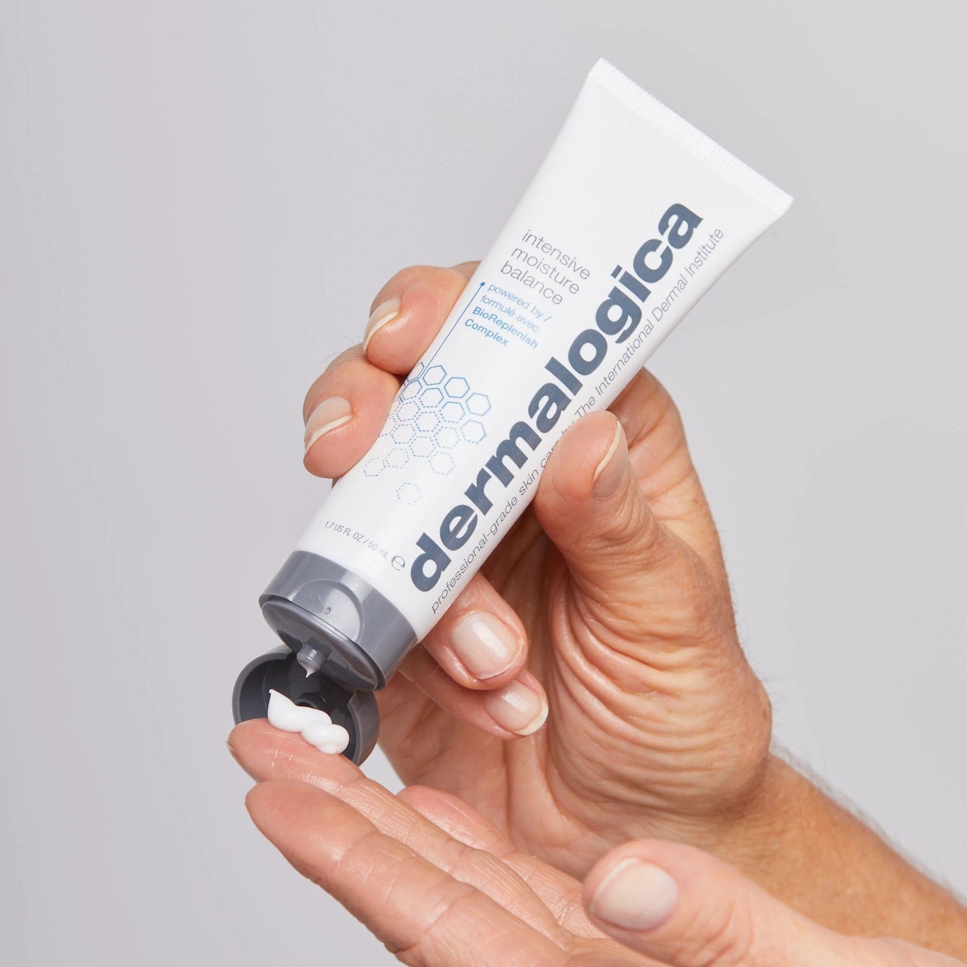 Hand hält eine Tube Intensive Moisture Balance Creme, aus der ein kleiner Tropfen auf den Fingerspitzen gedrückt wird.